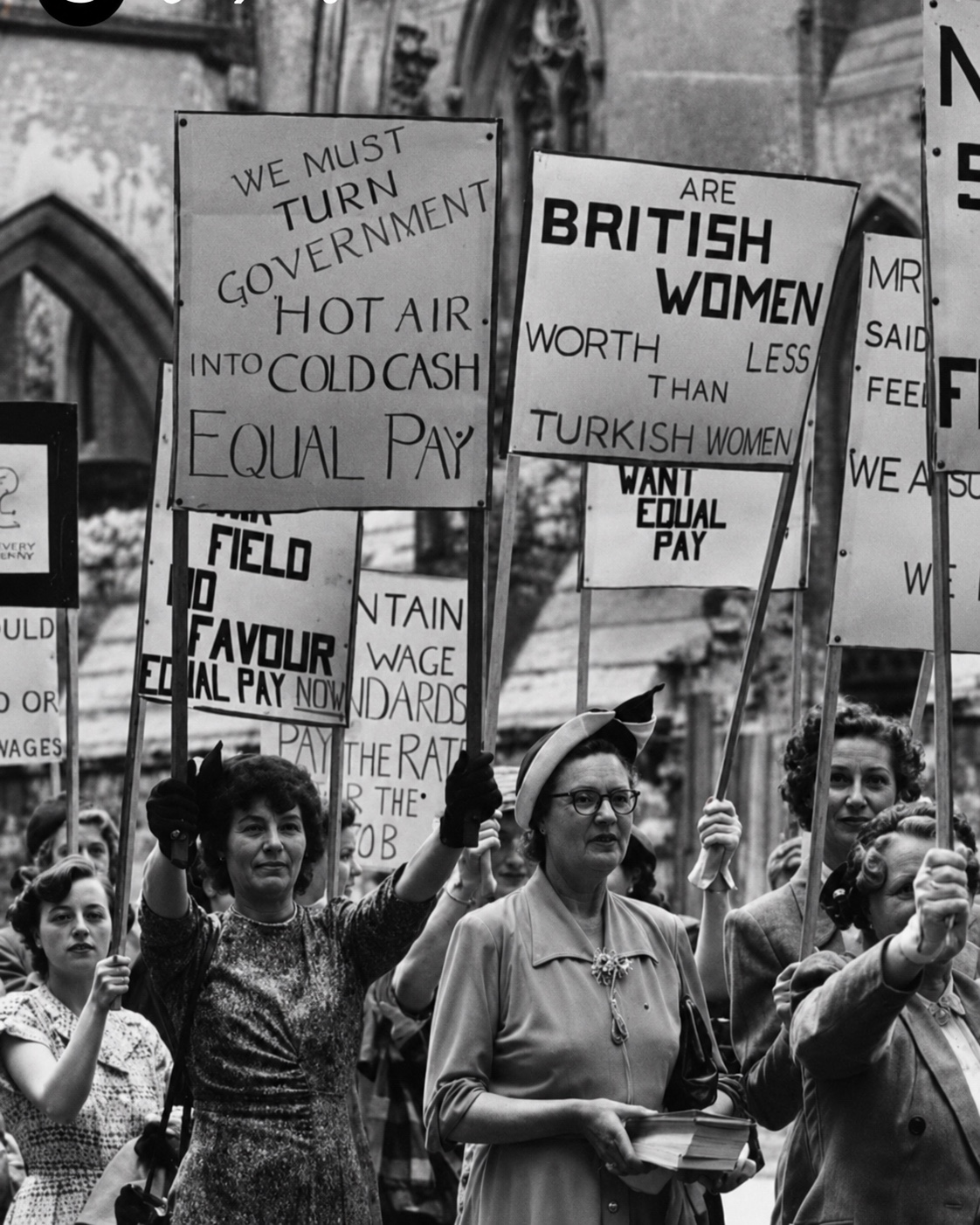 Women march with equal-pay placards in a black-and-white archival photograph