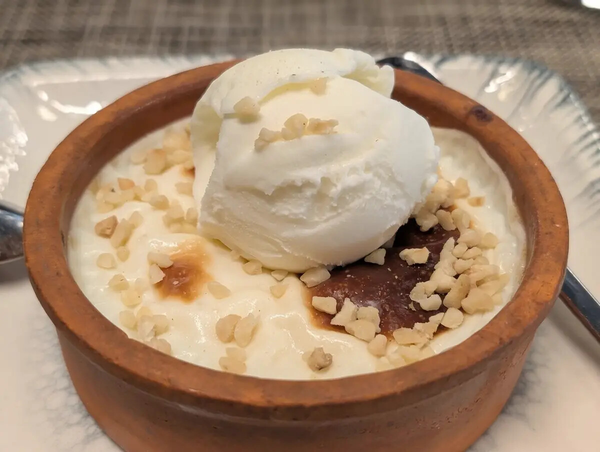 A clay-bowl dessert finished with ice cream and nuts